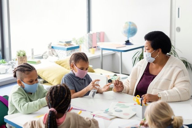 Kinder desinfizieren ihre Hände im Klassenzimmer