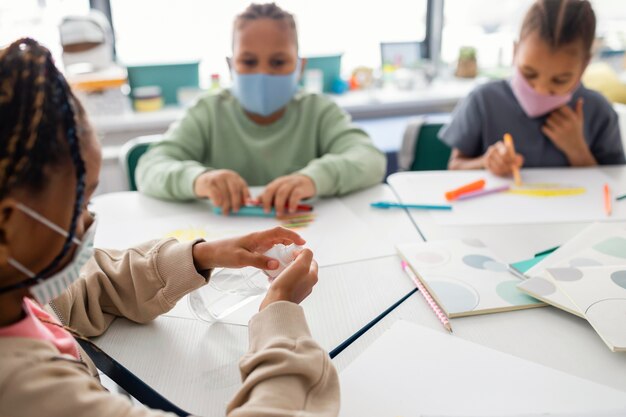 Kinder desinfizieren ihre Hände im Klassenzimmer