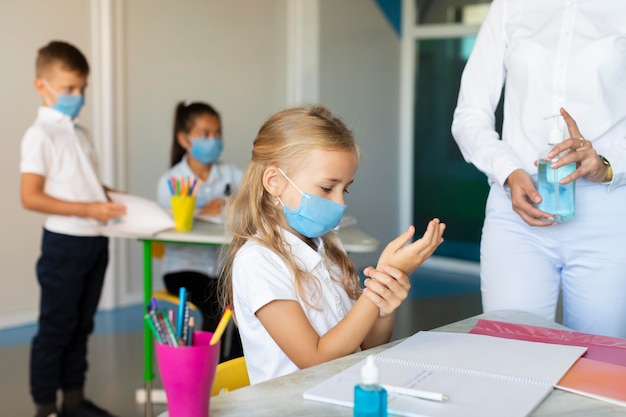 Kinder desinfizieren ihre Hände vor dem Unterricht