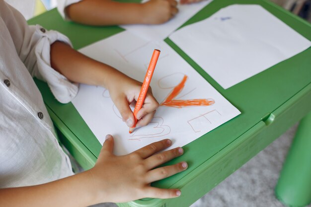 Kinder, die am grünen Tisch und am Zeichnen stationieren