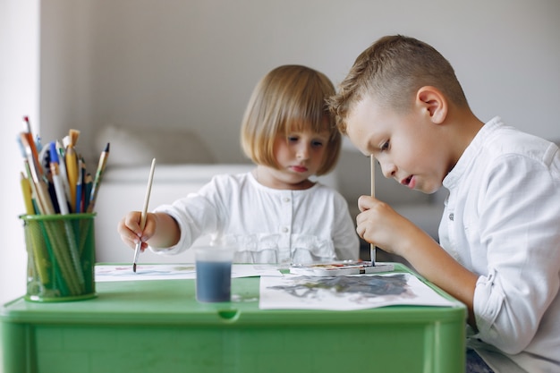 Kinder, die am grünen Tisch und am Zeichnen stationieren
