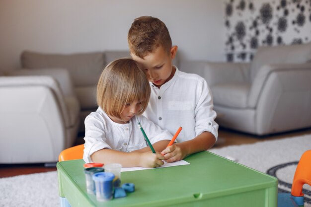 Kinder, die am grünen Tisch und am Zeichnen stationieren