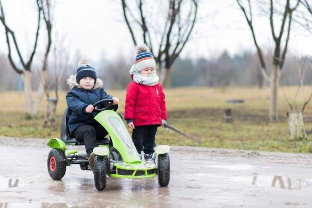 Kinder, die draußen mit grünem Wagen spielen