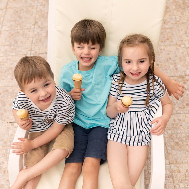 Kinder, die Eis essen, während sie auf Sonnenliege sitzen