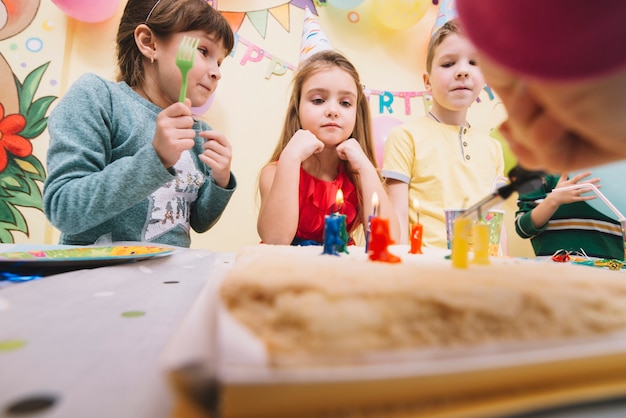 Kinder, die Geburtstagskuchen betrachten