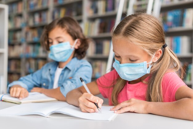 Kinder, die Hausaufgaben machen, während sie Gesichtsmasken tragen