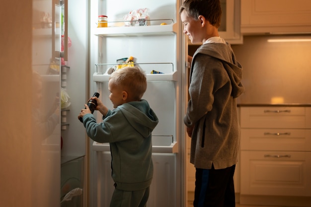 Kinder, die in den Kühlschrank schauen, mittlere Aufnahme