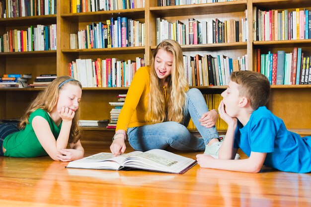 Kinder, die interessantes Buch in der Bibliothek studieren