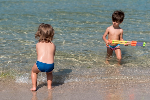 Kinder, die mit Wasserwerfern am Strand spielen