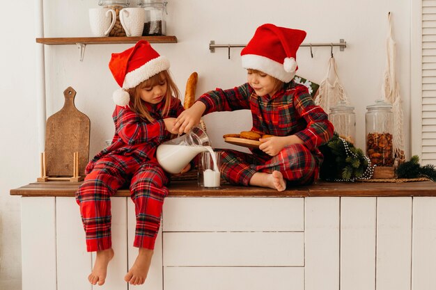 Kinder essen Weihnachtsplätzchen und trinken Milch