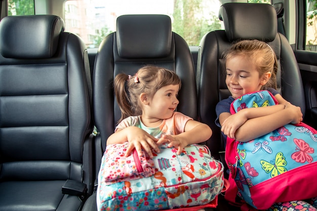 Kinder im Auto gehen zur Schule, fröhliche, süße Gesichter von Schwestern