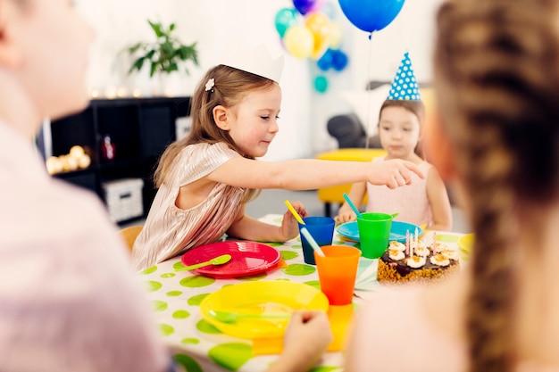 Kinder in den lustigen Kappen, die am Tisch sitzen