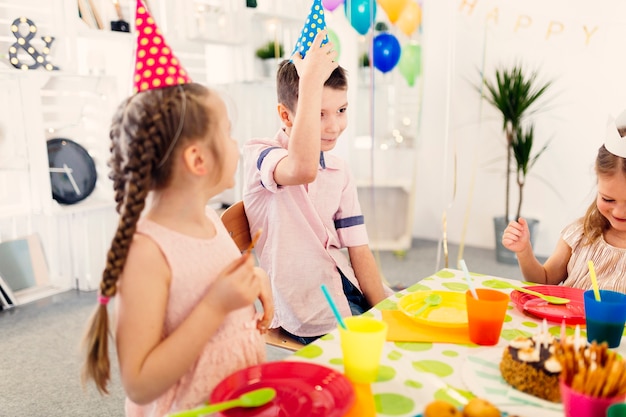 Kinder in der farbigen Kappe, die am Tisch sitzt