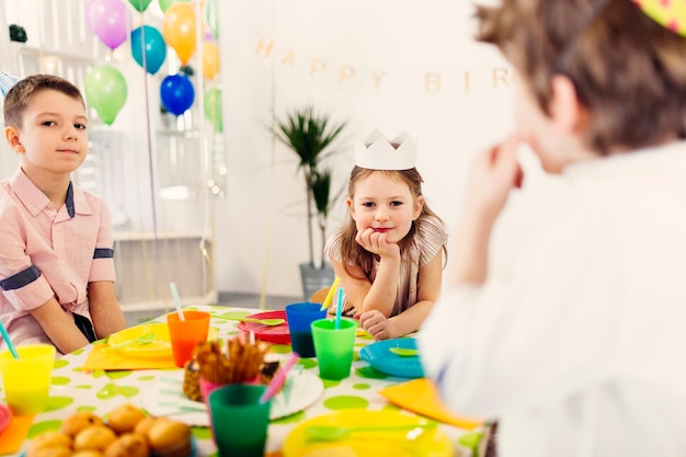 Kostenloses Foto kinder in farbigen kappen am tisch sitzen