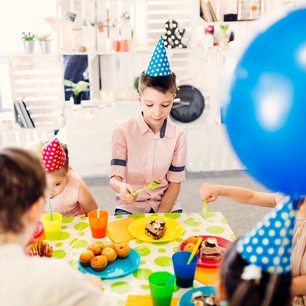 Kinder in farbigen Kappen am Tisch sitzen