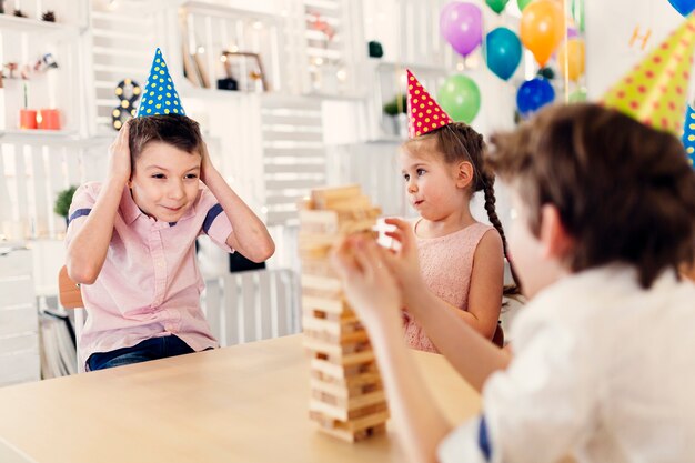 Kinder in farbigen Kappen, die hölzernes Spiel spielen