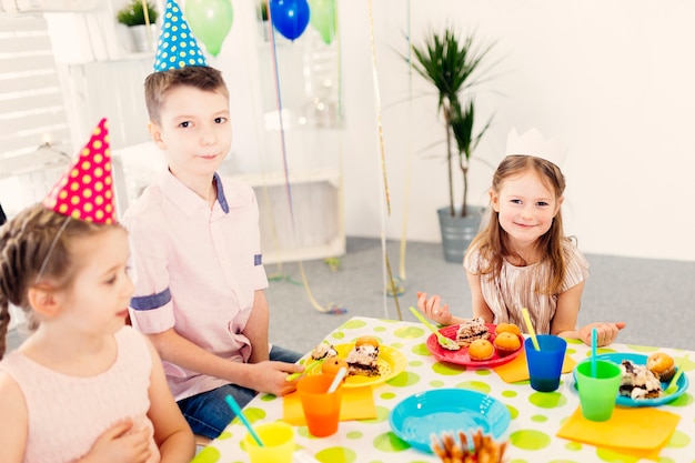 Kinder in farbigen Kappen, die Kamera betrachten