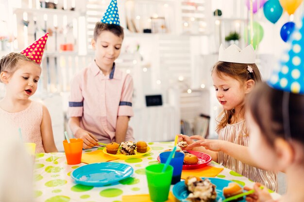 Kinder in farbigen Kappen, die Spaß haben