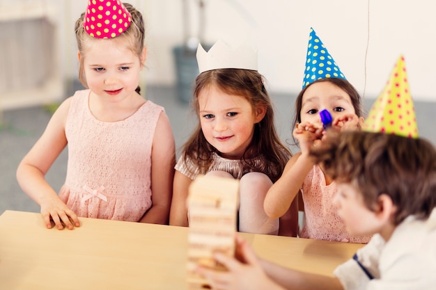 Kinder in farbigen Kappen, die Spielzeug spielen