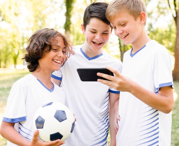 Kinder in Sportbekleidung, die ein Telefon betrachten