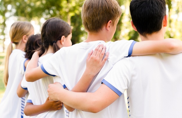 Kinder in Sportbekleidung halten sich gegenseitig fest