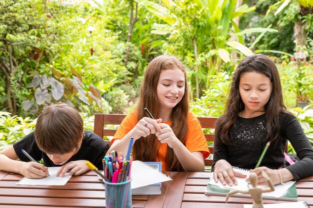 Kinder Junge und Mädchen machen Hausaufgaben und zeichnen zusammen im Garten zu Hause