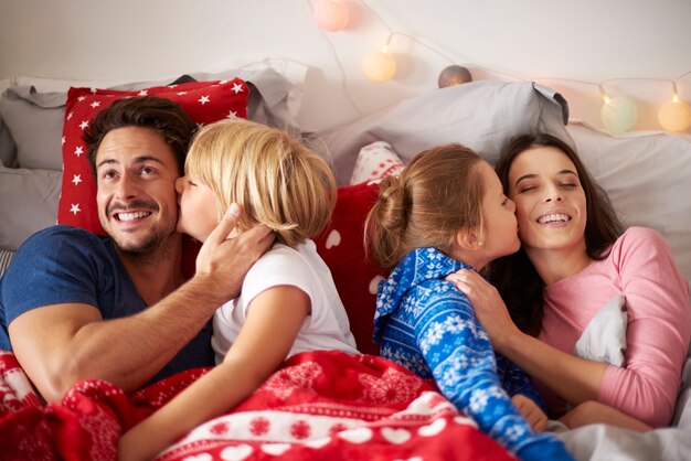 Kinder küssen ihre Eltern im Bett