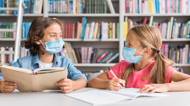 Kinder machen ihre Hausaufgaben, während sie eine medizinische Maske tragen
