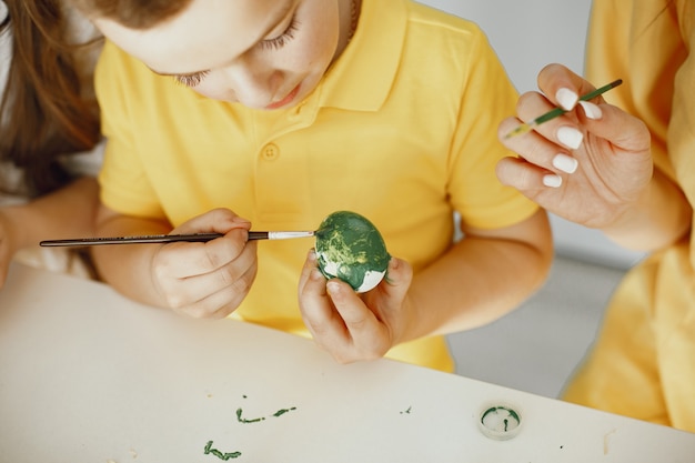 Kostenloses Foto kinder malen eier. mutter unterrichtet kinder. an einem weißen tisch sitzen.