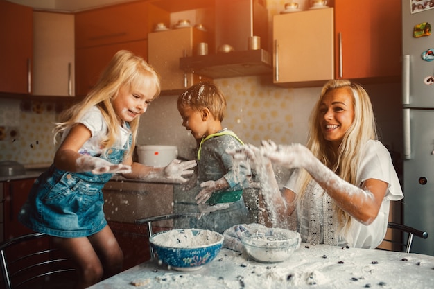 Kinder mit ihrer Mutter kochen und wirft Mehl