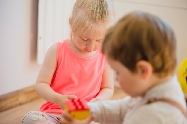 Kinder sitzen auf dem Boden spielen