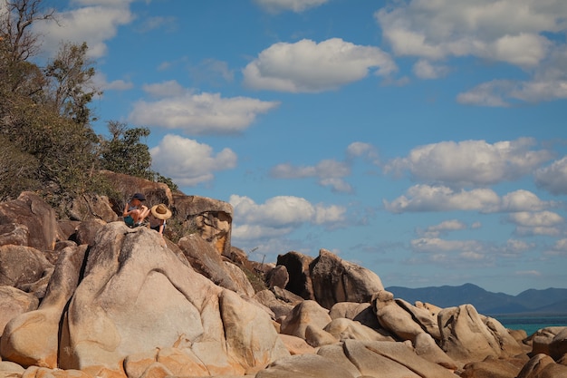 Kinder sitzen auf den großen Felsen am Strand