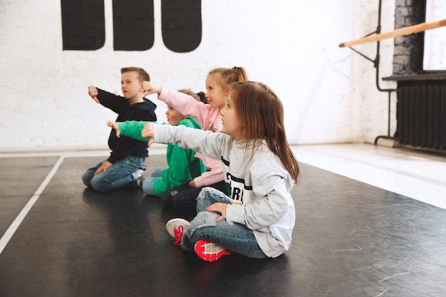 Kinder sitzen in der Tanzschule. Ballett-, HipHop-, Street-, Funky- und Modern-Tänzer-Konzept.