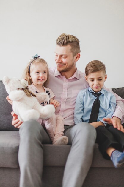 Kinder sitzen mit ihrem Vater auf dem Sofa