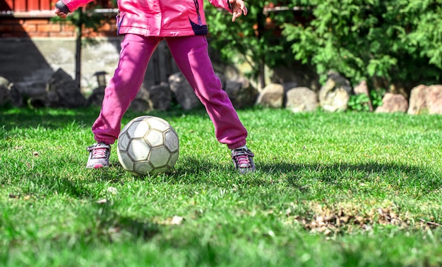Kinder spielen Fußball auf dem Rasen, halten ihren Fuß auf dem Ball.