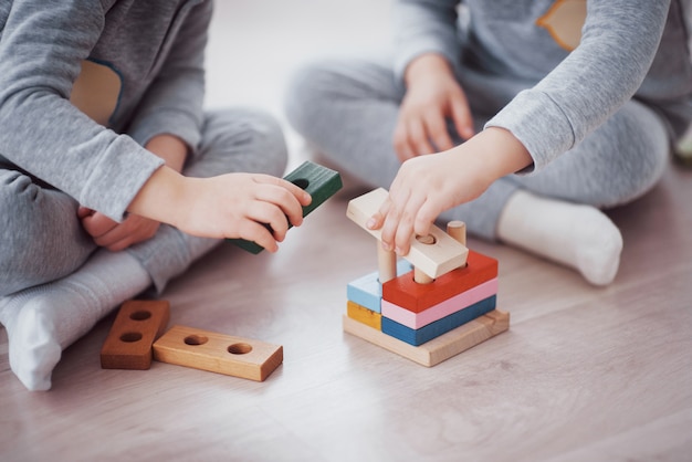 Kinder spielen mit einem Spielzeugdesigner auf dem Boden des Kinderzimmers. Zwei Kinder spielen mit bunten Blöcken. Kindergarten-Lernspiele