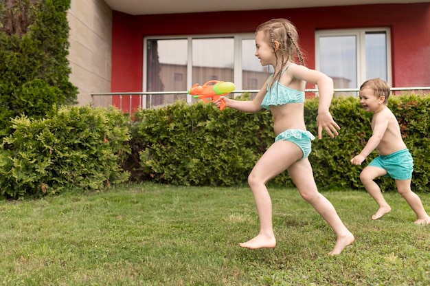 Kinder spielen mit Wasserpistolen am Pool