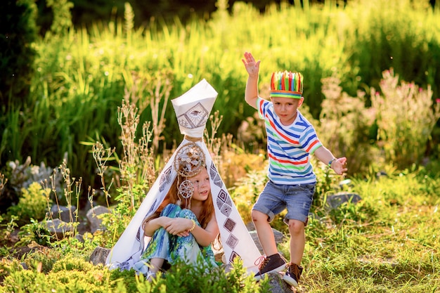 Kinder spielen wie amerikanische Ureinwohner auf grünem Gras auf dem Gebiet