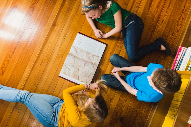 Kinder studieren Karte auf dem Boden sitzen