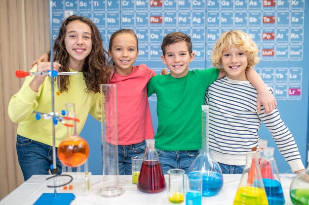 Kinder umarmen sich im Chemieunterricht und schauen in die Kamera