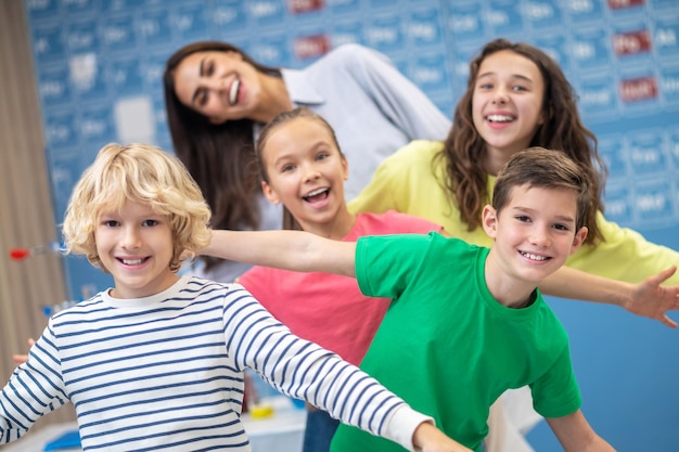 Kinder und Lehrer in verspielter Stimmung lächeln in die Kamera