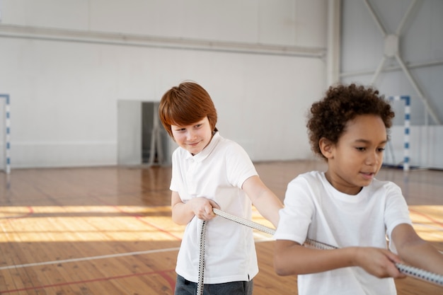 Kostenloses Foto kinder ziehen seil im fitnessstudio, mittlerer schuss