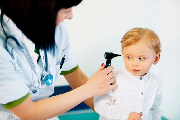 Kinderarzt macht Ohruntersuchung des kleinen Mädchens