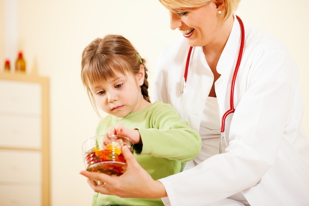 Kinderarztdoktor, der dem kleinen patienten süßigkeit gibt