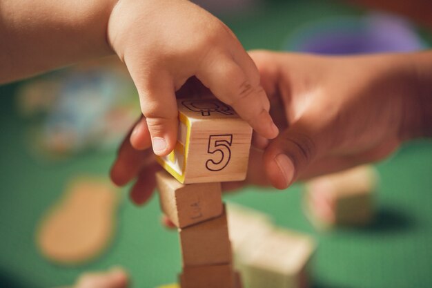 Kinderhand nimmt einen Holzblock mit der Nummer 5 auf