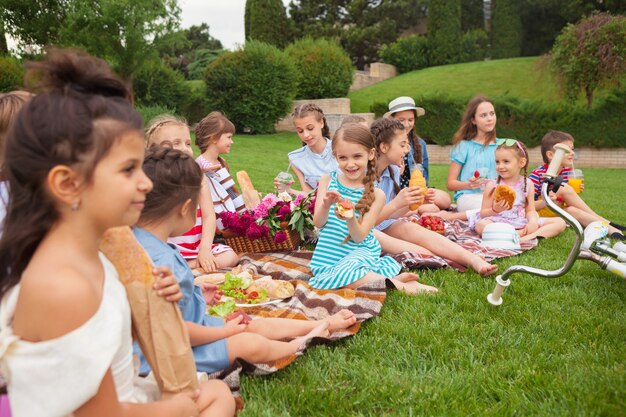 Kindermode-Konzept. Gruppe von jugendlich Mädchen, die am grünen Gras am Park sitzen