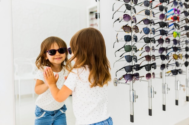 Kindertragende Sonnenbrille und Schauen im Spiegel