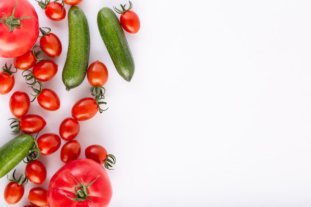 Kirsche Tomaten rot frisch reif mit roten Tomaten und grünen Gurken auf weißem Hintergrund