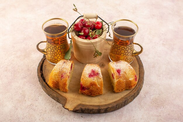 Kirschkuchenscheiben von oben mit Kirschen und Tee auf dem rosa Schreibtischkuchen-Kekszuckersüß