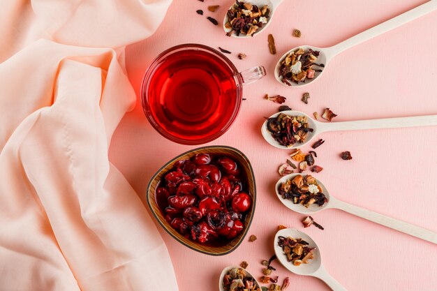 Kirschmarmelade mit getrockneten Kräutern, Tee in einer Schüssel auf Textil und Pink